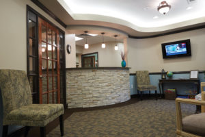 Stacked stone on the check-in desk, and spa-like wall colors of light blue and green are cheerful and relaxing. Patients enjoy comfortable chairs while watching the large screen screen TV.