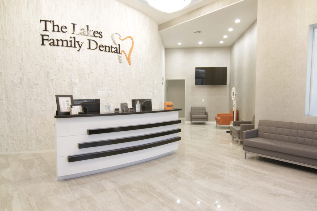 Patients enter an elegant reception area, decorated in neutral grays and soft whites with black and orange highlights.